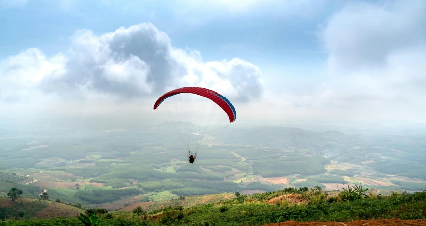 a person on a hillside flying a red parachute