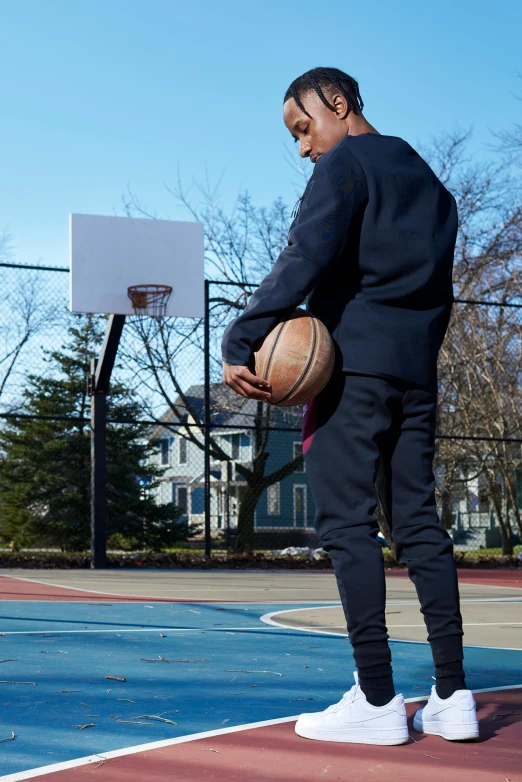 a young man standing on a basketball court holding a ball