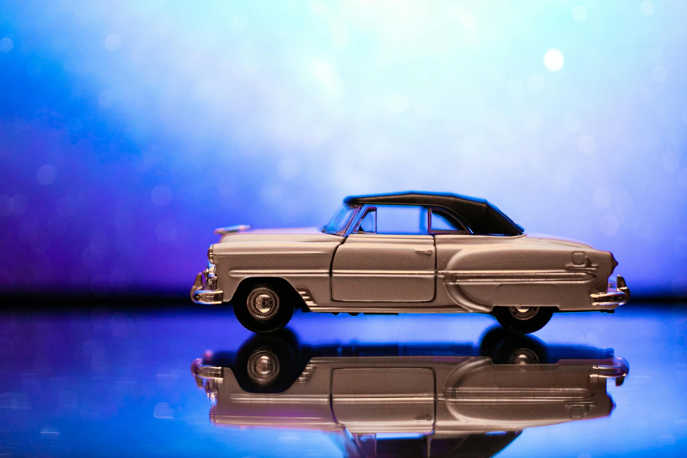 toy car parked next to glass on reflective surface