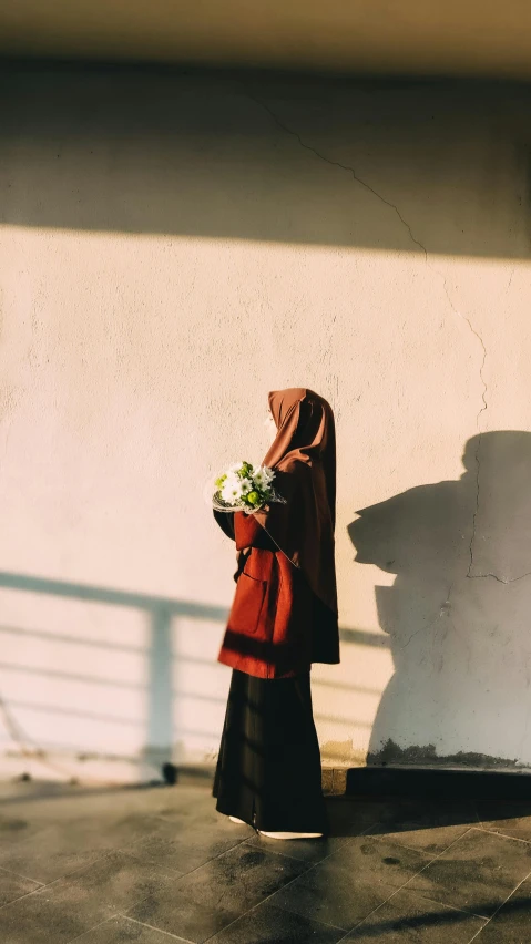 the woman is standing on a sidewalk in front of the wall