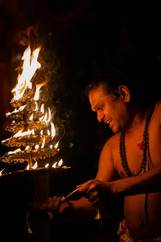 man in headdress lighting torches in dark area