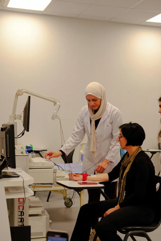 two people at a desk look at a person in a headscarf