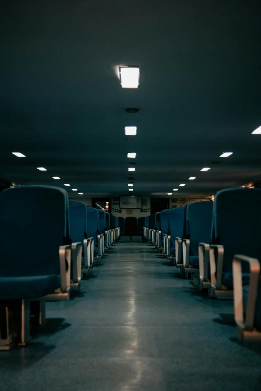 a dark room with a very long blue seat