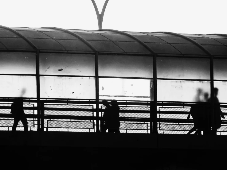 the silhouettes of two people walking across a bridge