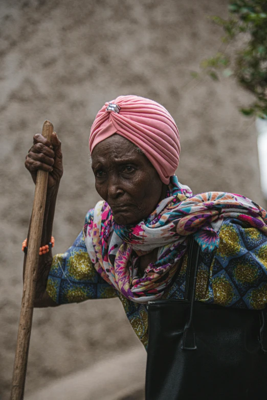 an african woman holding a stick in her right hand