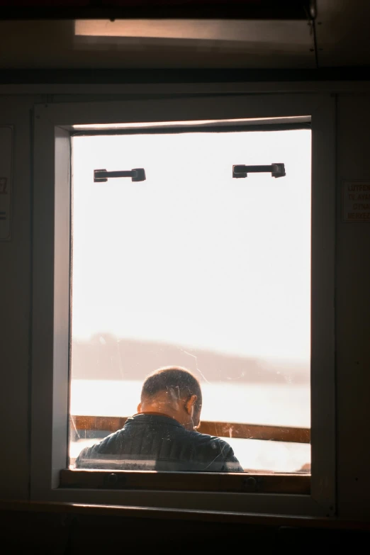 the man in the blue sweater is looking out a window