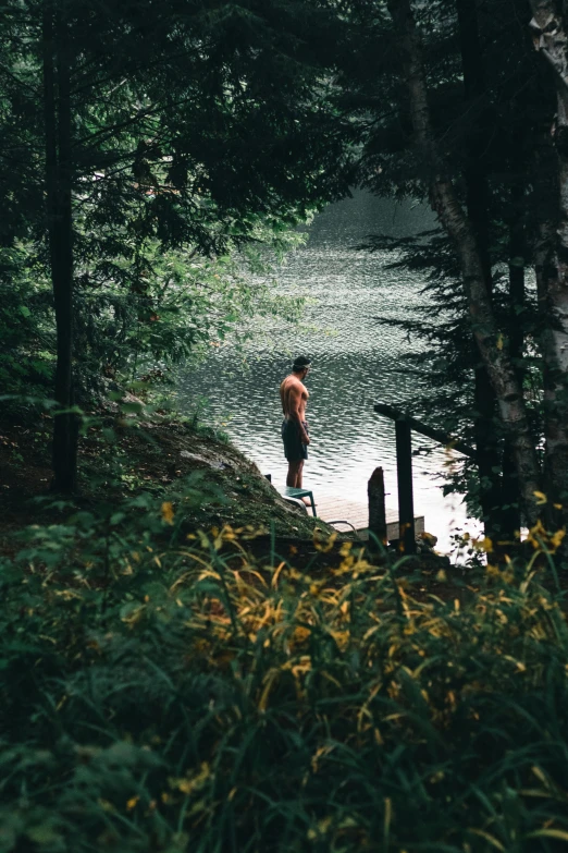 the man is standing on a log next to the water