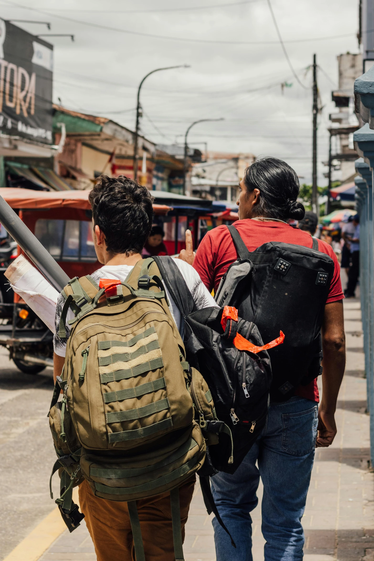 two men are walking down the street with their back packs on