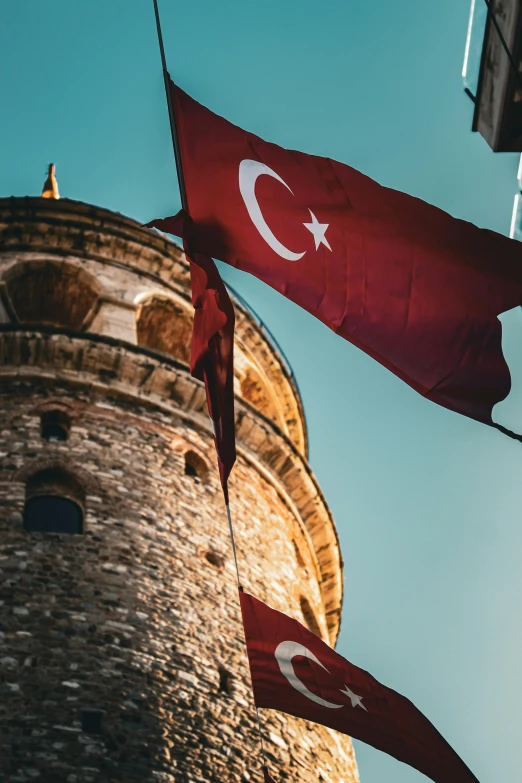 three red flags next to an old tower