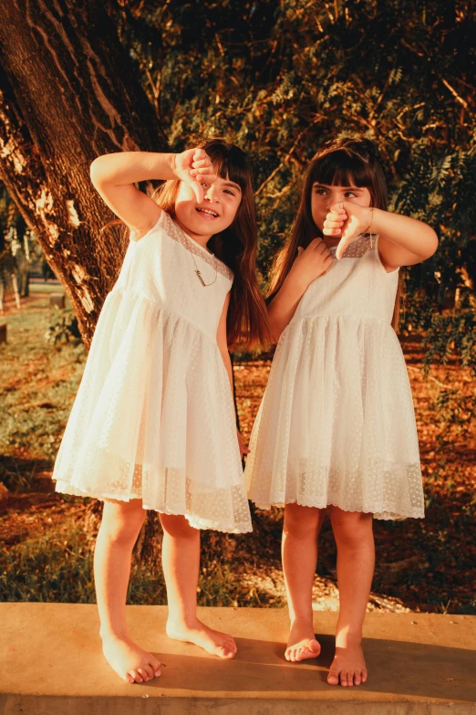 two little girls dressed in white and one is wearing a dress