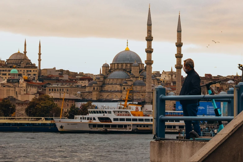 man standing on wall looking over river with city skyline in background