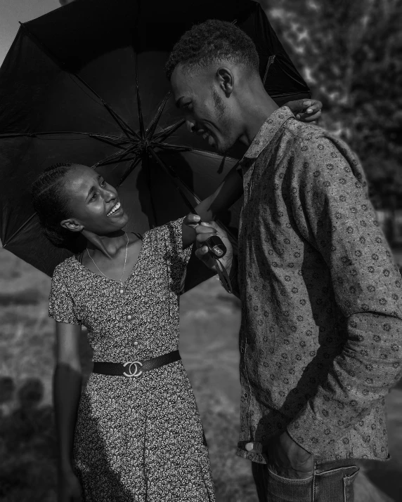 black and white po of a woman standing under a large umbrella next to an adult