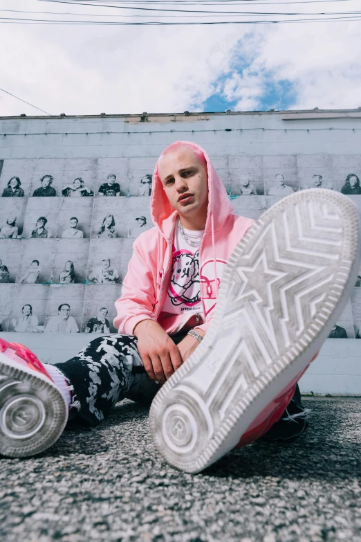 young man with pink hoodie sitting on cement