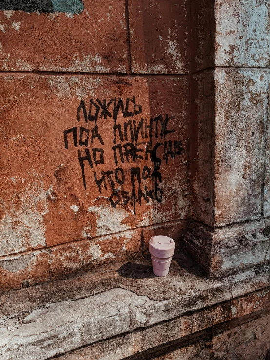 a small pink cup sitting on the side of a wall