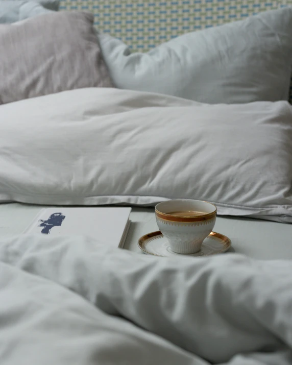 a cup sitting on top of a bed with white sheets