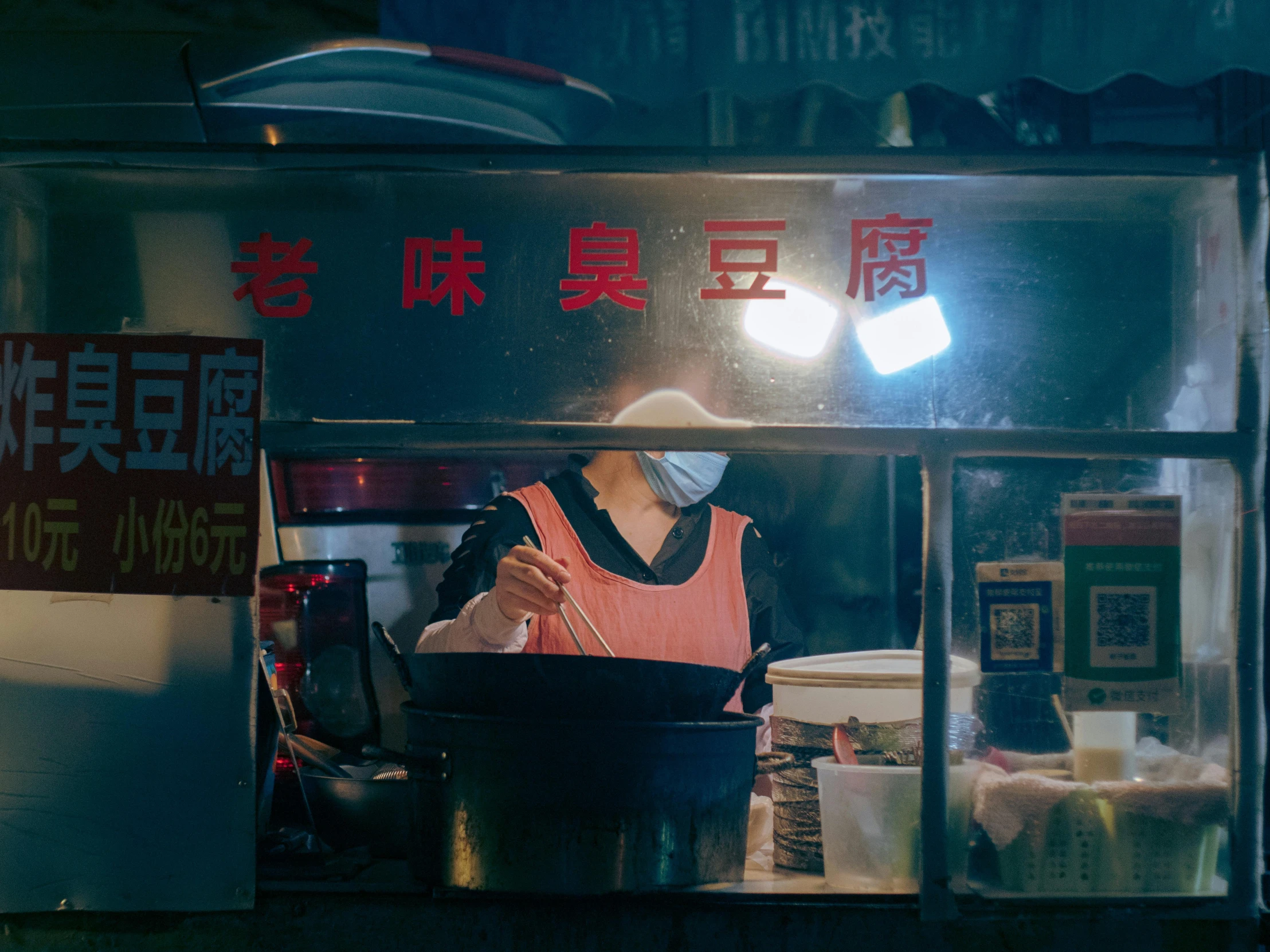 an asian street vendor preparing food in front of a light