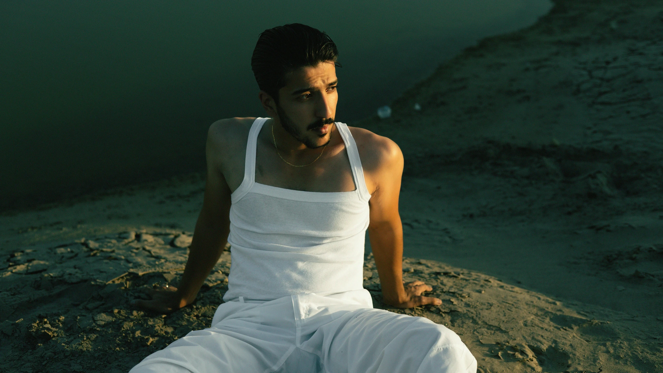 a man sitting on top of a hill with one hand to his face