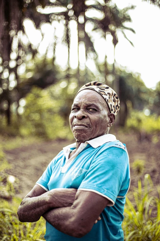 an old woman standing in the woods wearing a blue shirt