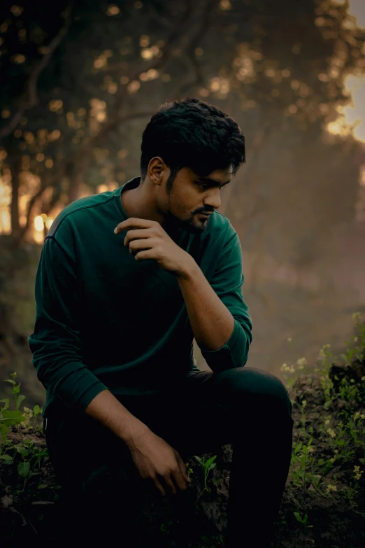 a man sitting in a forest posing for a po