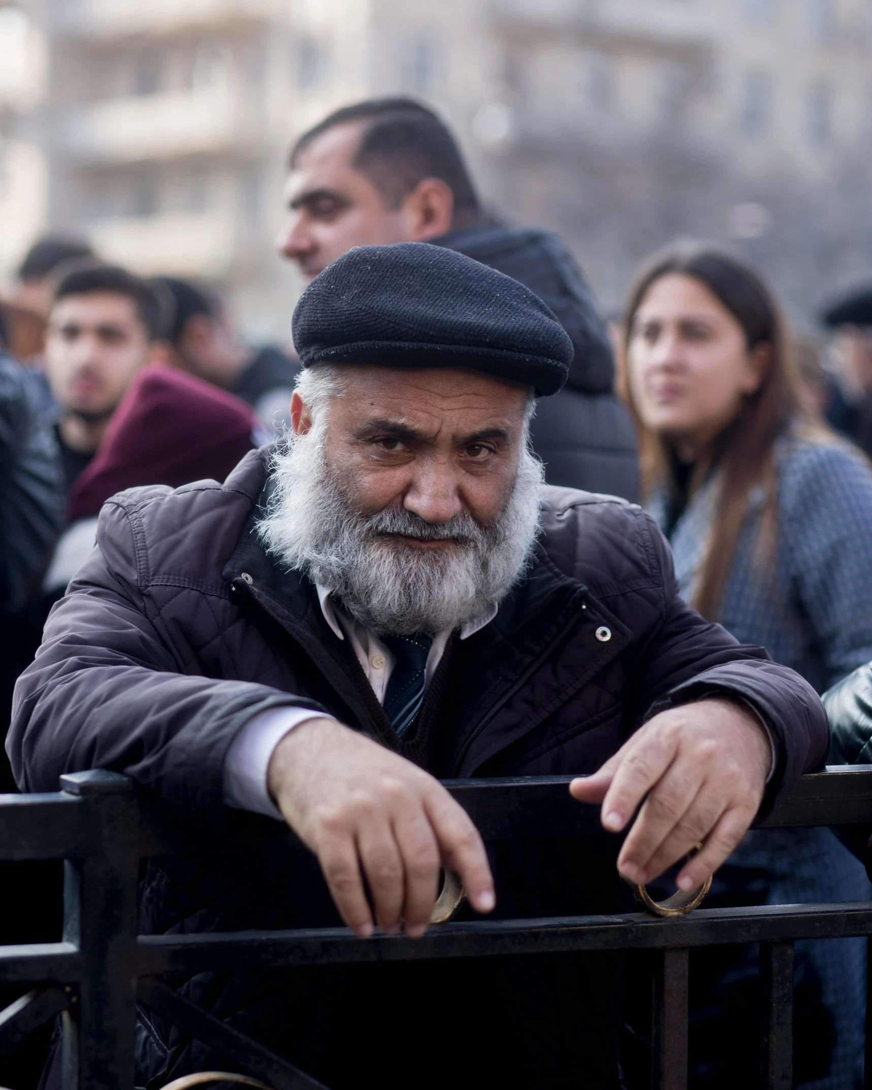 a man in a grey cap is holding his hand on a fence