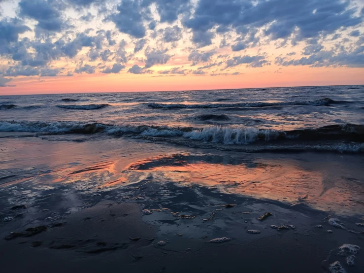 the sun is setting on the beach near the water