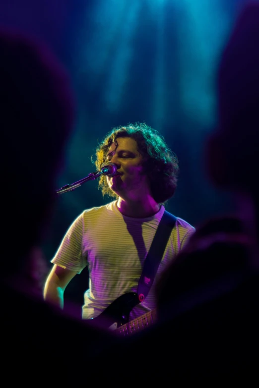 a man standing on stage with a microphone and singing into the microphone