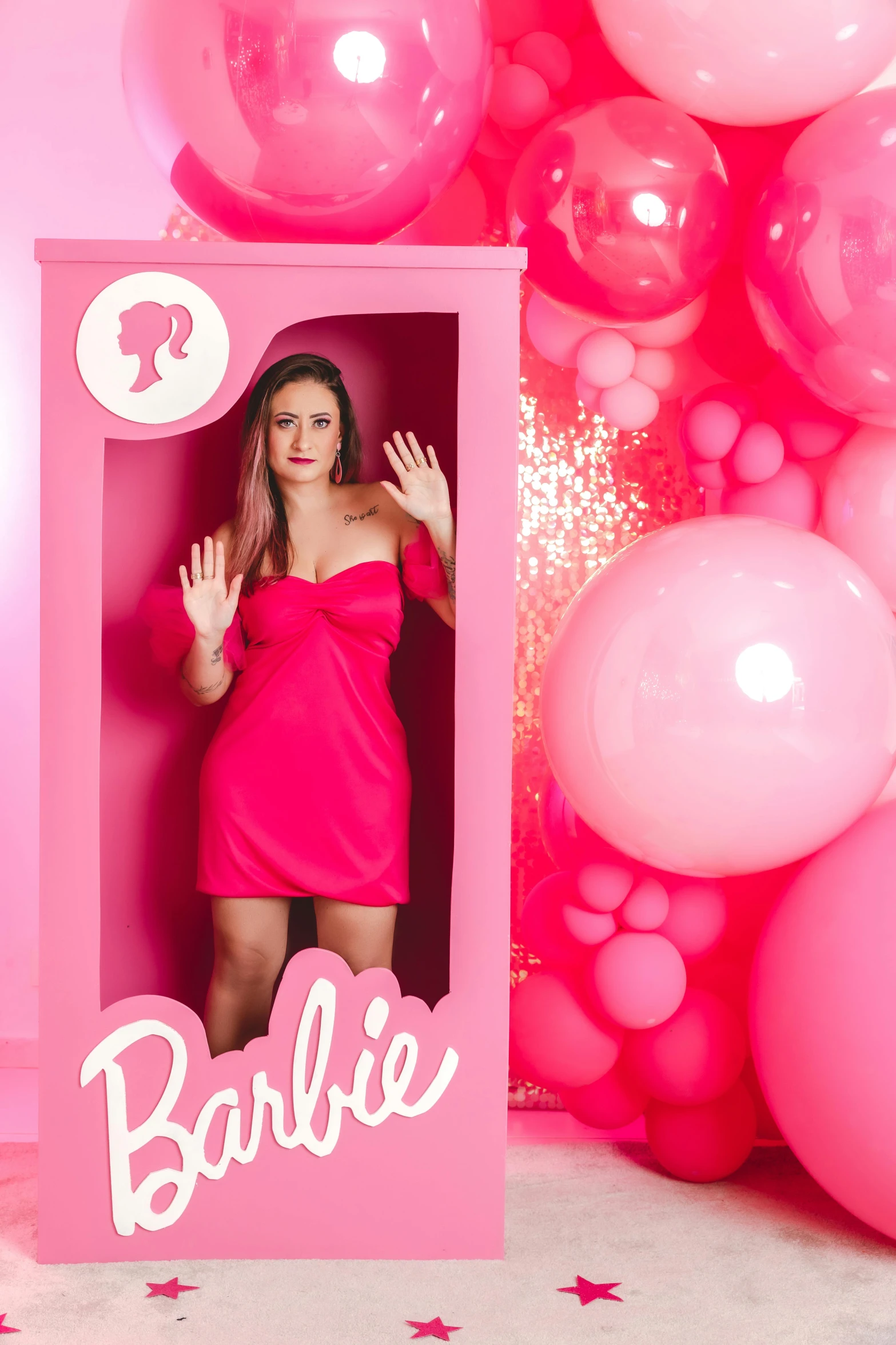 woman in pink dress posing in frame surrounded by balloons