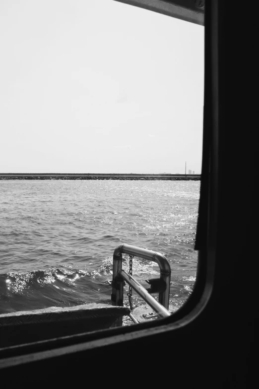 the view of a body of water is shown from an empty bus window
