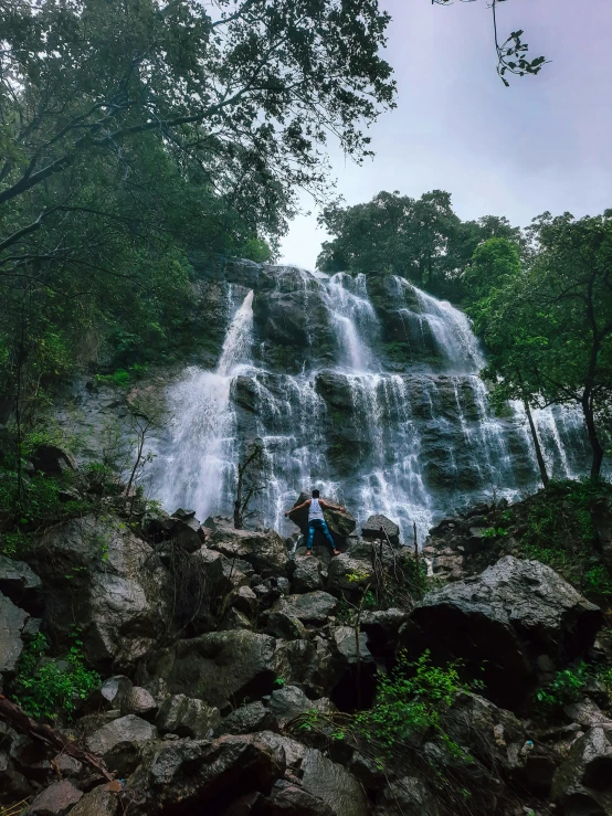 two people pose for the camera as they stand near a waterfall