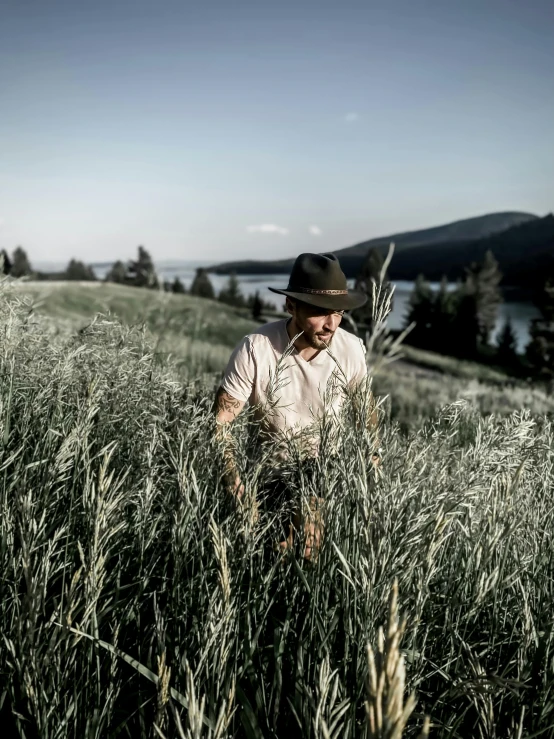 a man wearing a hat standing in the middle of a field