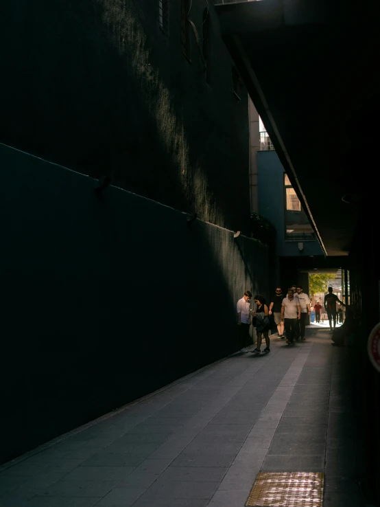 people are walking down the sidewalk in the dark