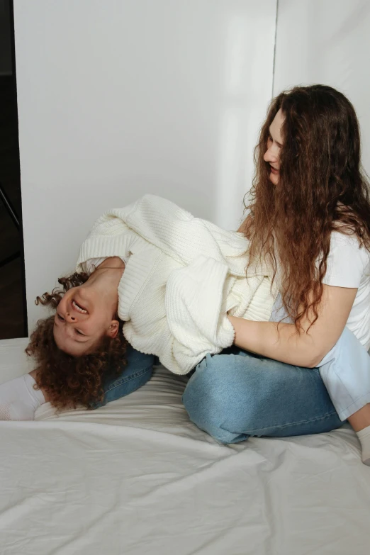 woman laying on the bed looking up at another women lying upside down