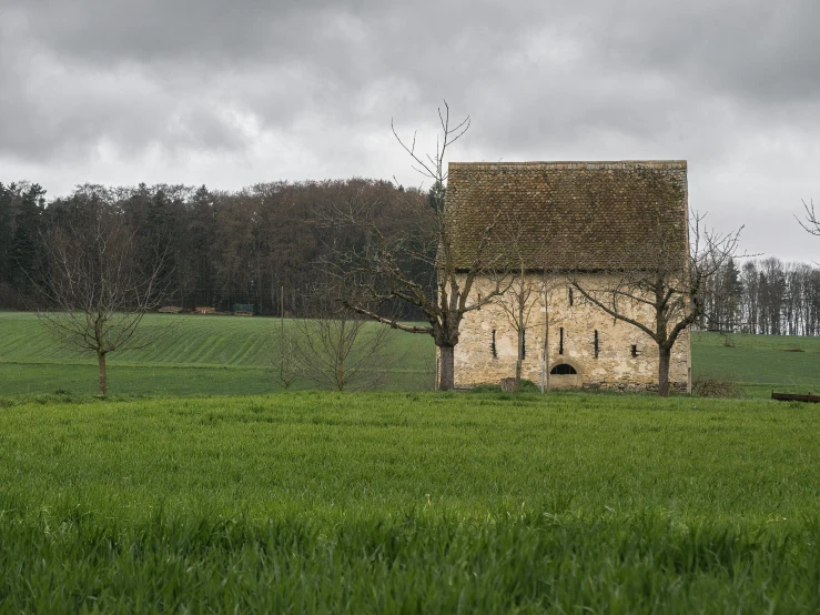 this is a small rustic style house in the middle of a green field