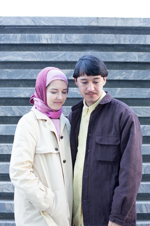 a young man and woman standing next to each other in front of a building