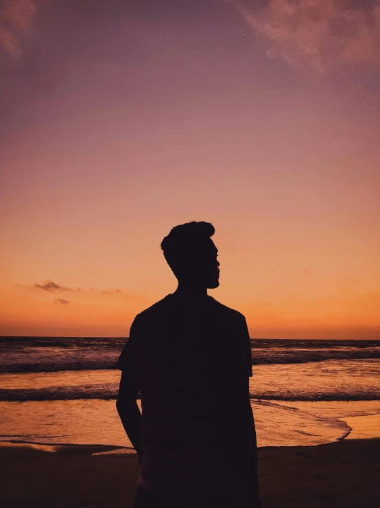 the silhouette of a person standing on the beach