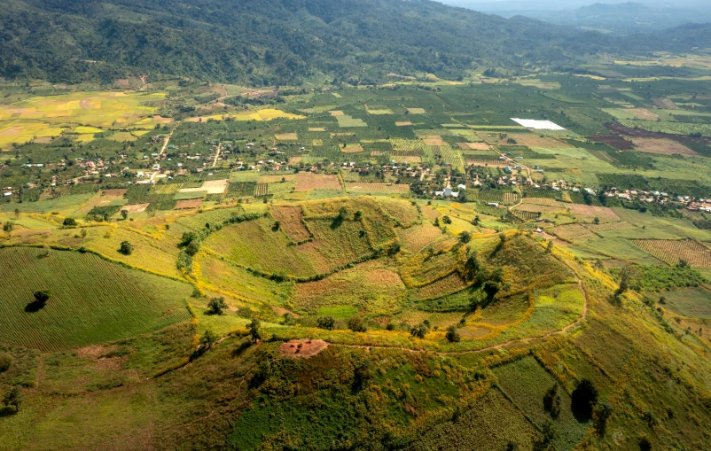 an aerial view shows rolling hills and roads, while houses can be seen in the distance