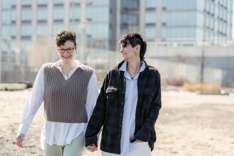 two young women smile as they walk together in a field