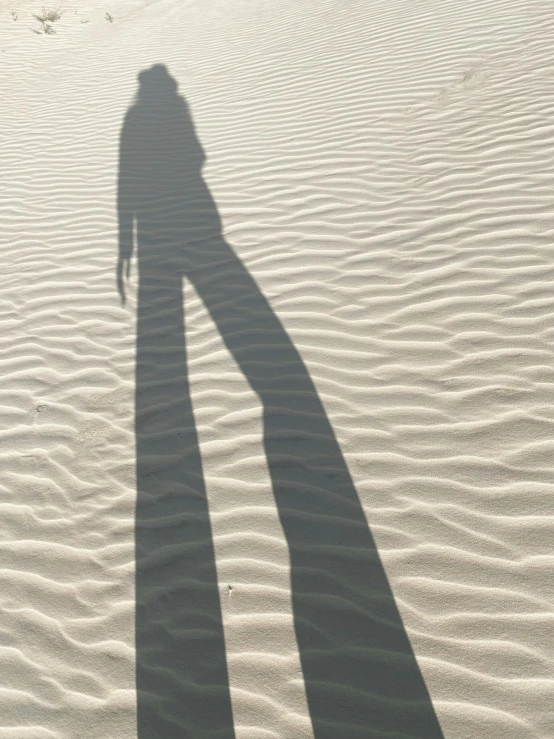 a shadow of a person standing in the sand