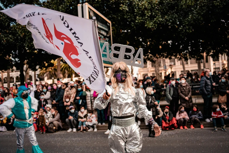 two women dressed in astronaut costumes hold a banner as people look on