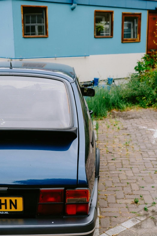 a rear view of a car parked near a blue building