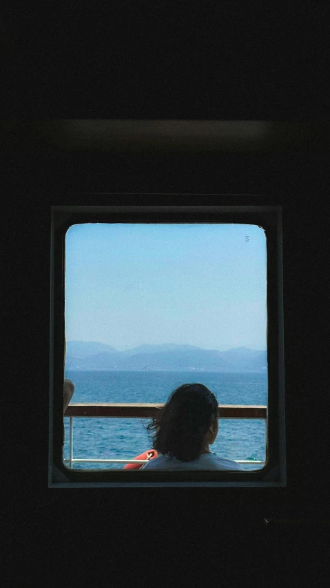 person looking out of a window at the ocean