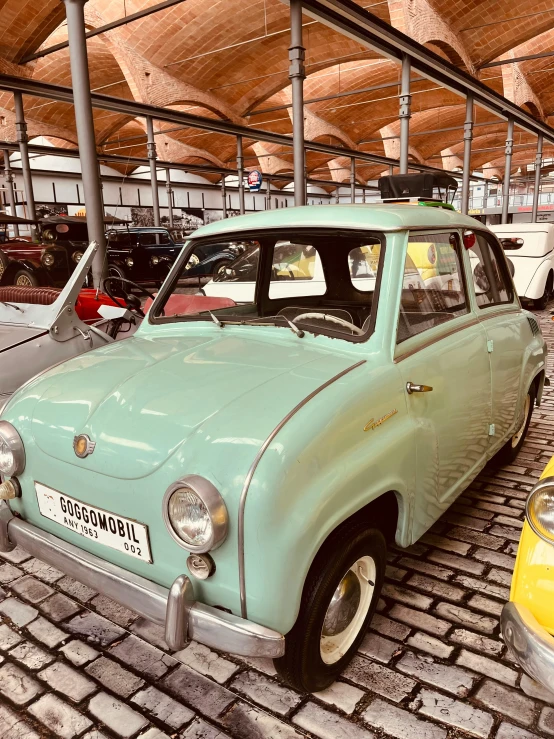 three different old - fashioned cars are parked in an indoor parking lot