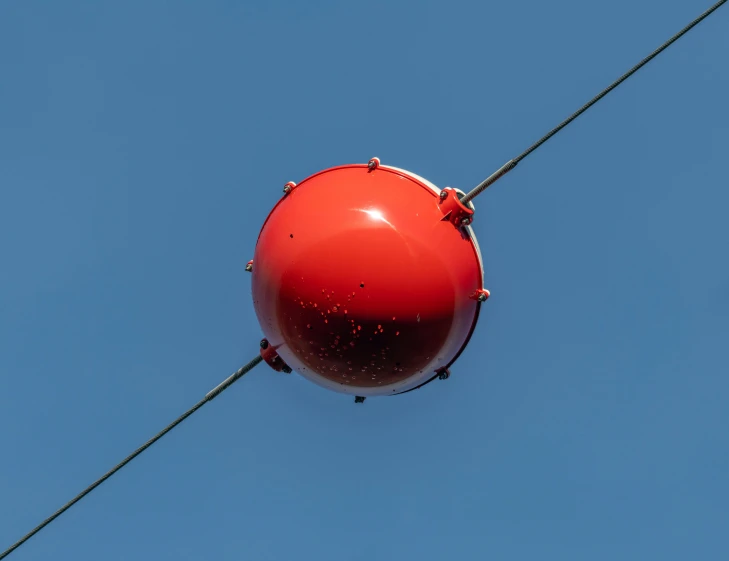 an orange object hangs in a clear blue sky