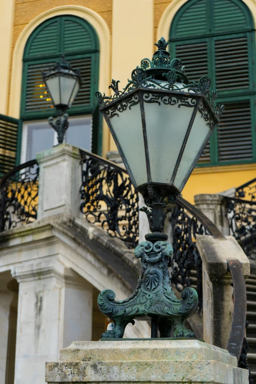 an ornate lamp at the base of a statue outside an entrance