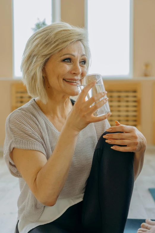 woman sitting on a floor holding a glass of water