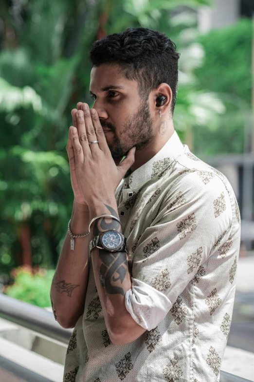 a man with his hands folded to his chest while standing