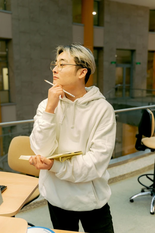 a man wearing glasses and a hoodie smoking a cigarette