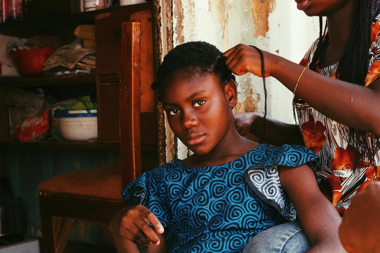 a woman sitting on the floor brushing another person's hair