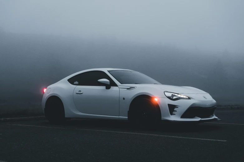 the front end of a white sports car in front of fog