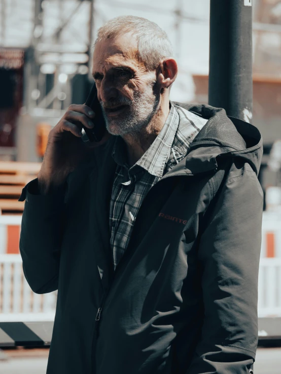 a man talking on his cell phone while wearing a grey coat